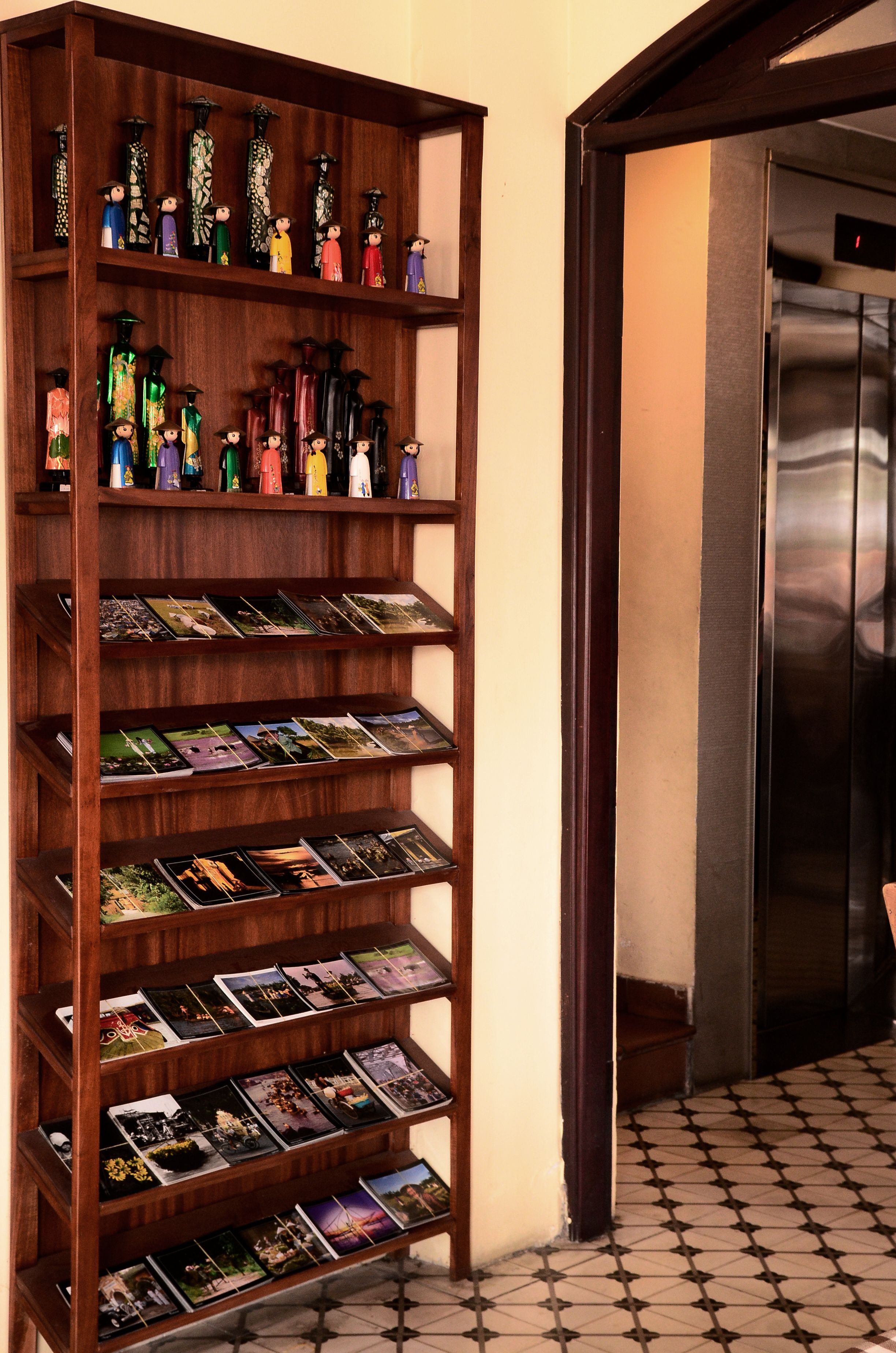 Una estantería de madera con postales y botellas decorativas.