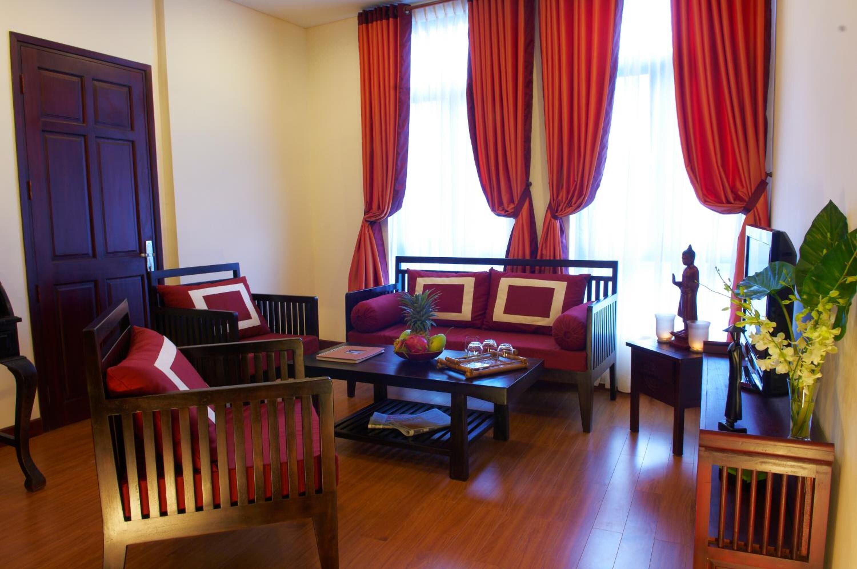 A room with a sofa, chairs, a coffee table with fruit, and a Buddha statue.