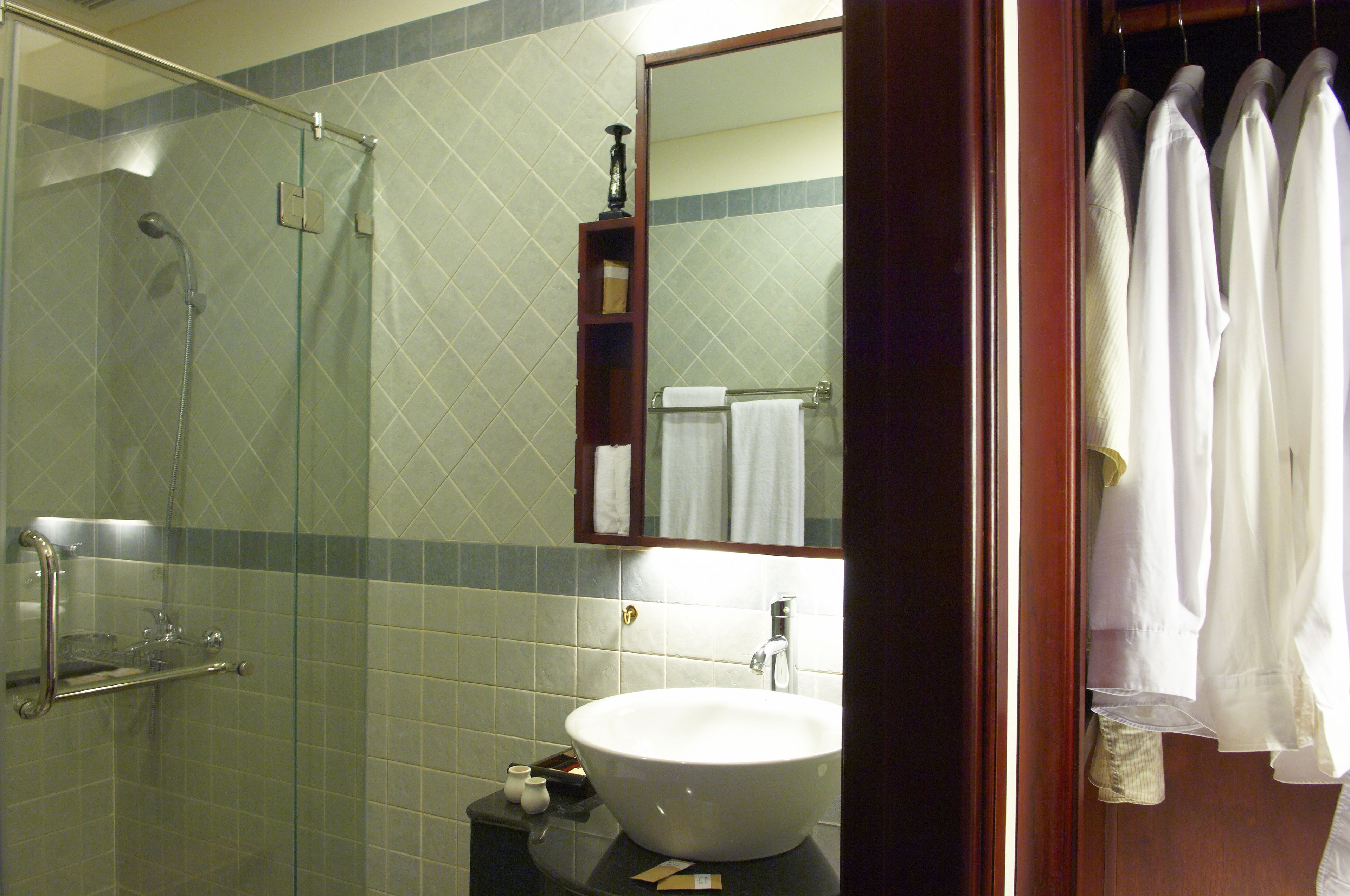 Une salle de bain avec une douche à parois de verre, un lavabo blanc et un miroir au-dessus.