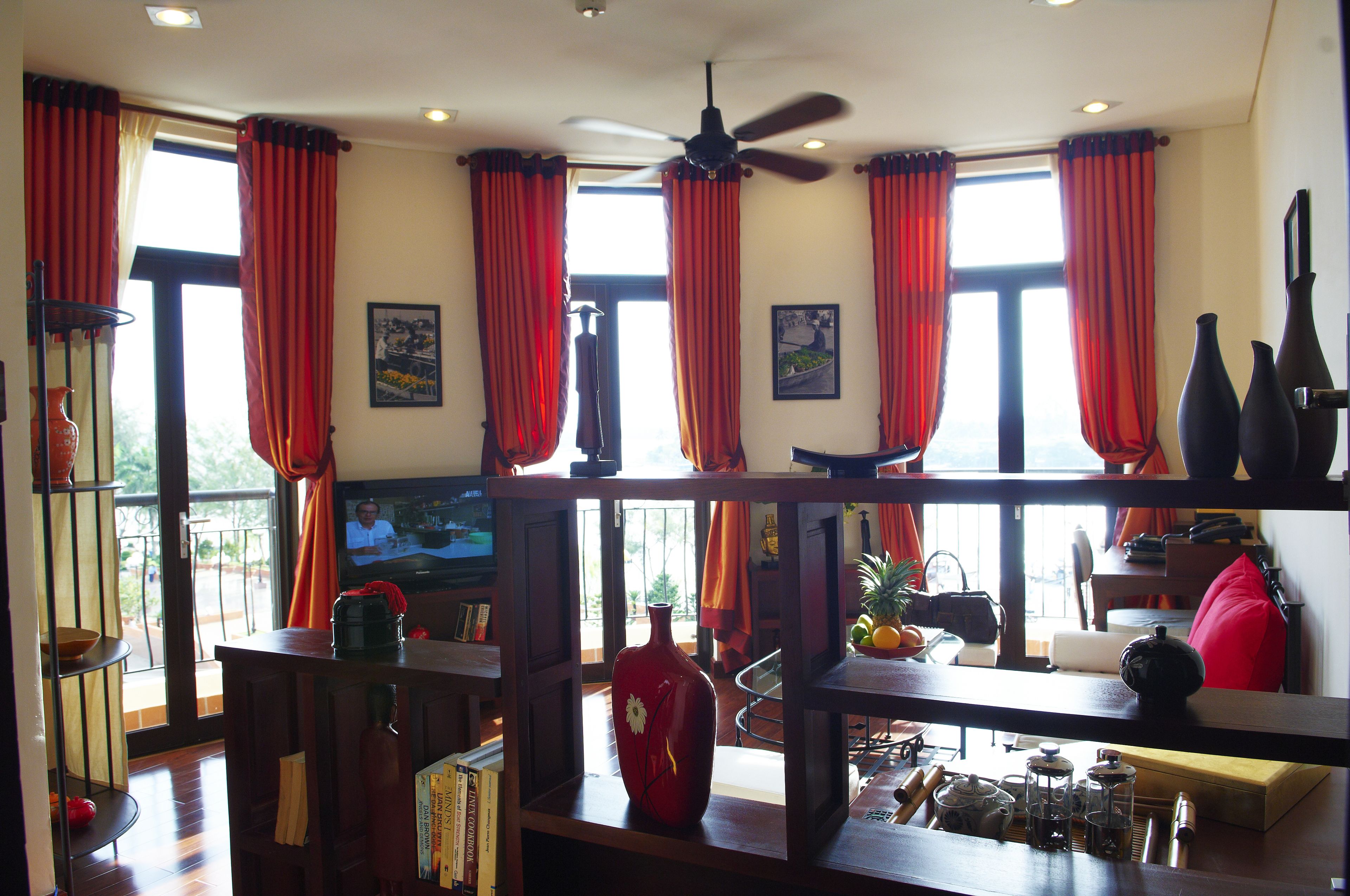A room with a TV, a red vase, and a ceiling fan.