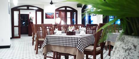 A restaurant with checkered tablecloths, wooden chairs, and a tiled floor.