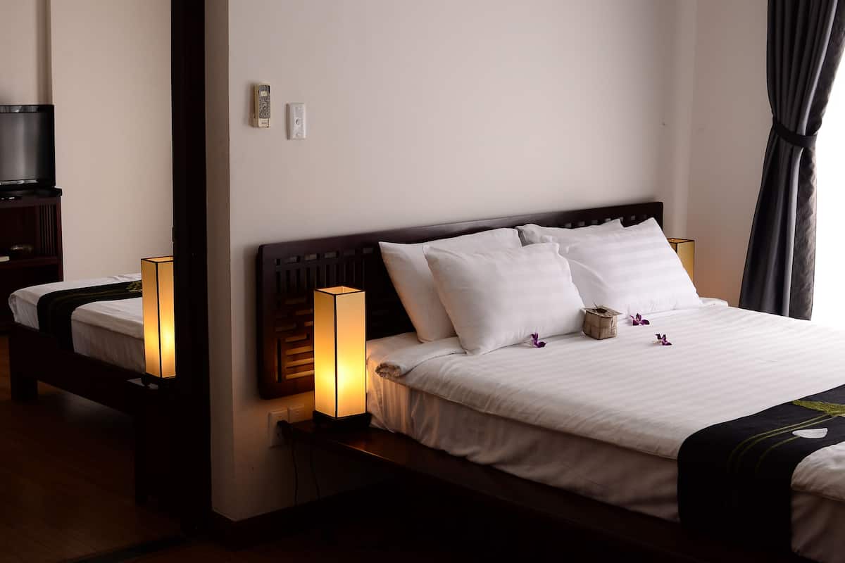 A hotel room with a large bed, bedside lamps, a TV, and a bedside table.