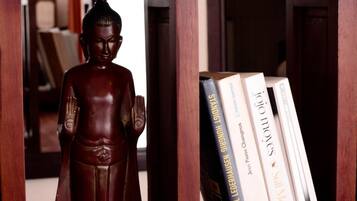 Una estantería de madera con una estatua de Buda, libros y un cartel de 'No Fumar'.