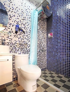 A bathroom with a toilet, a shower with a blue curtain, and a tiled wall with a mosaic pattern.