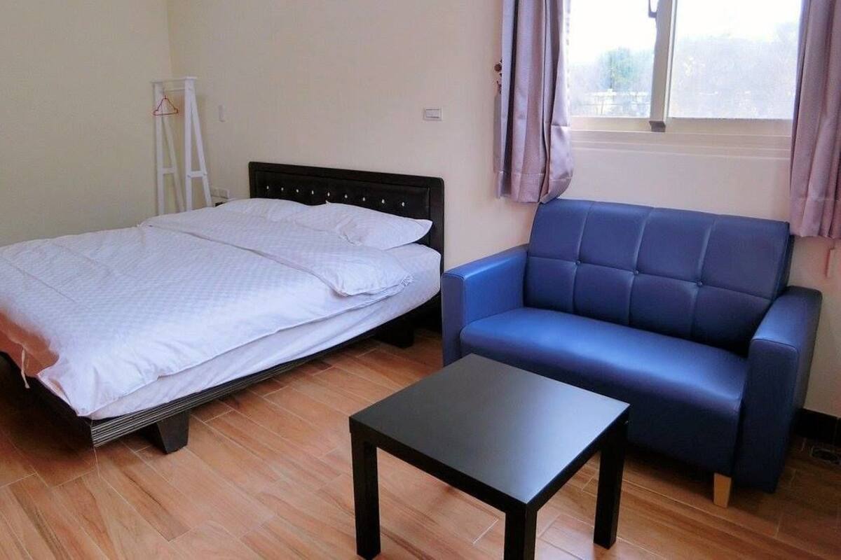 A bedroom with a bed, a blue sofa, and a small table.