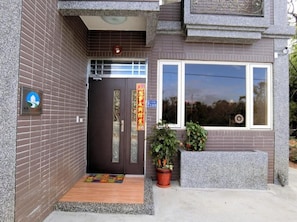A building entrance with a dark door, a small porch area, and a potted plant.