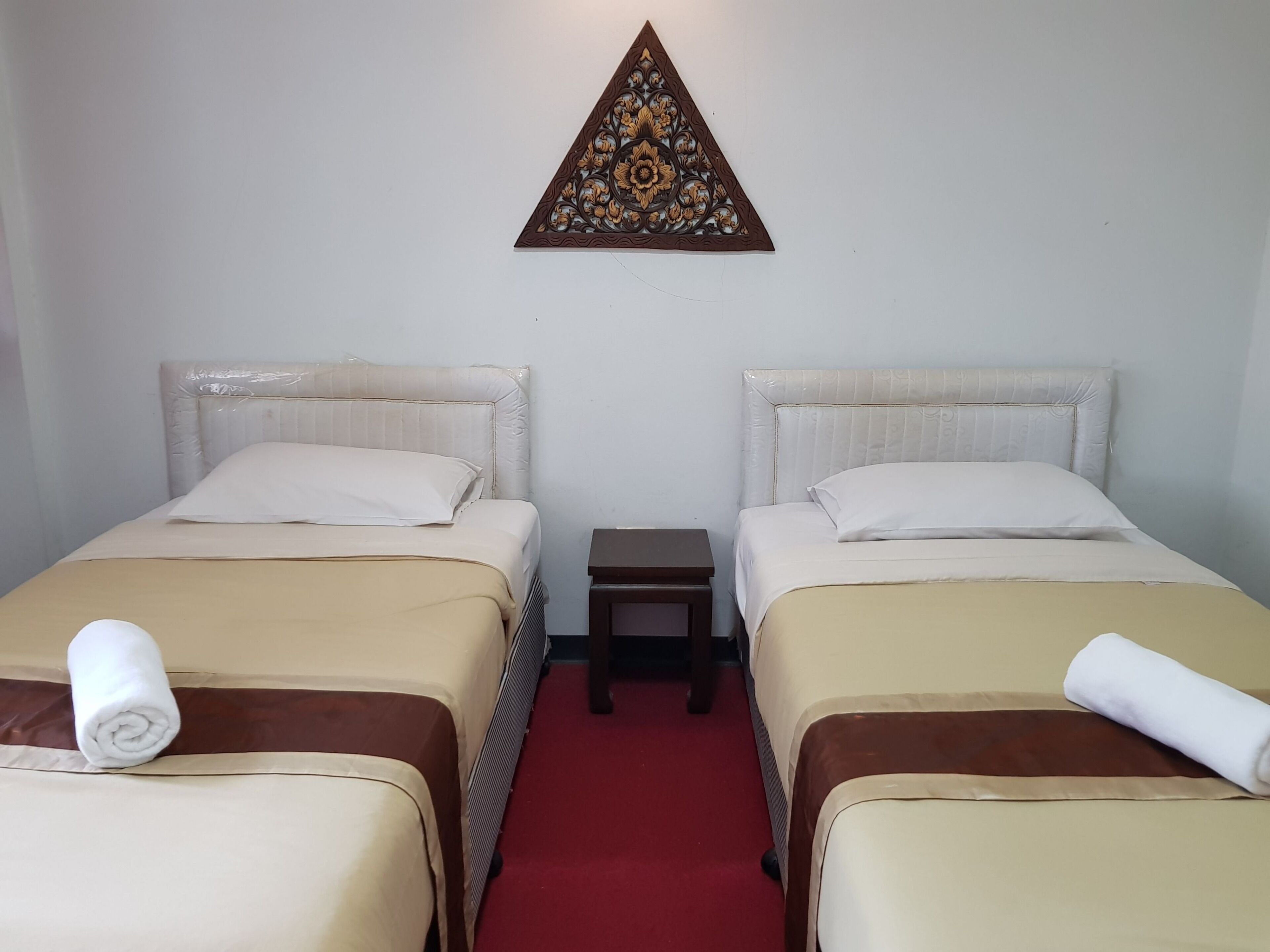 A hotel room with two beds, a small bedside table, and a decorative wall hanging.