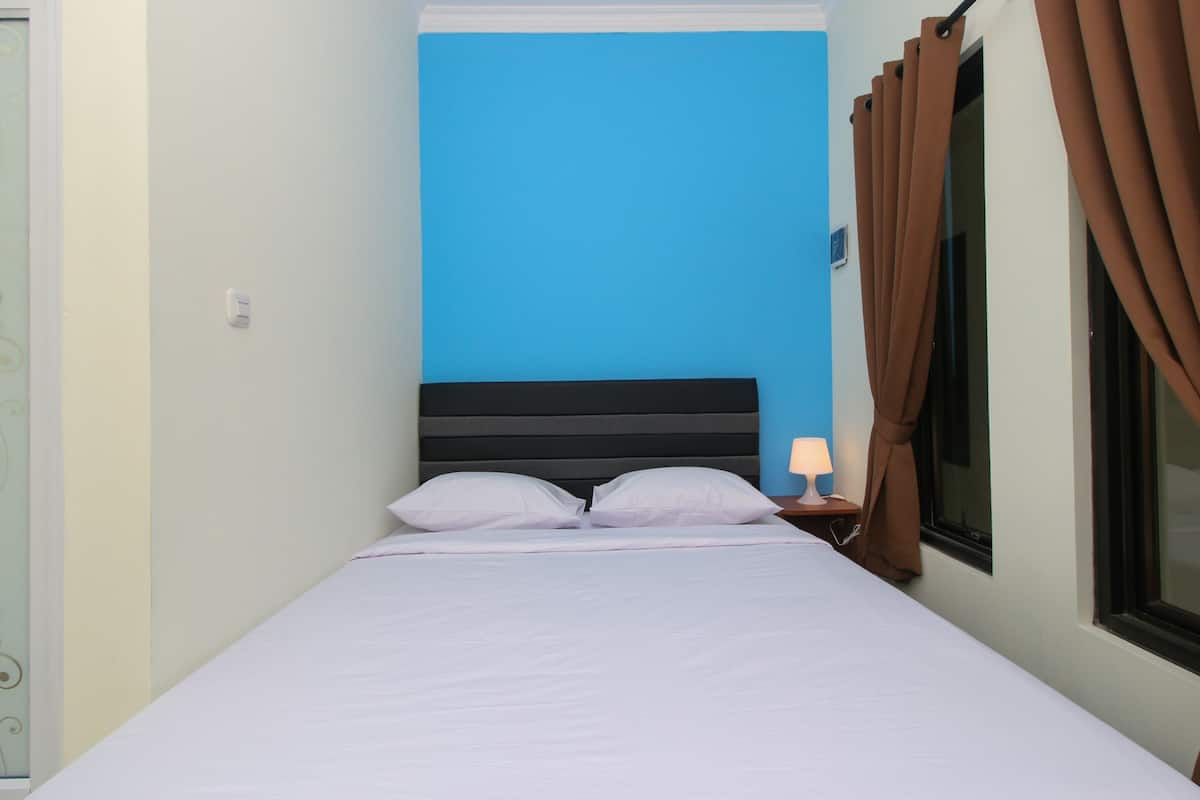 A bed with white linens, a black headboard, and a nightstand with a lamp.