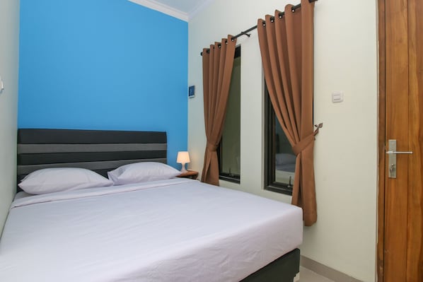 A hotel room with a bed, a nightstand, a lamp, and curtains.