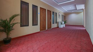 Un pasillo con suelo estampado en rojo, puertas de madera y plantas en macetas.