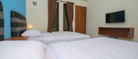 A hotel room with two beds, a TV on the wall, and a wooden shelf.