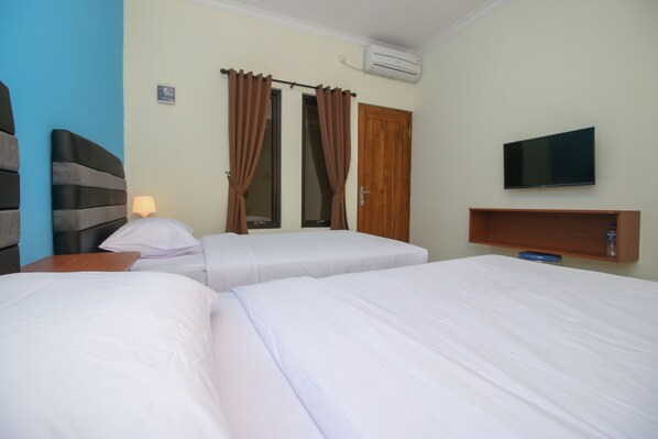 A hotel room with two beds, a TV on the wall, and a wooden shelf. - Sky Residence Syariah Mampang 1 Jakarta (Jakarta)