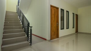 Un interior limpio y moderno con una escalera, puertas de madera y suelo de baldosas.