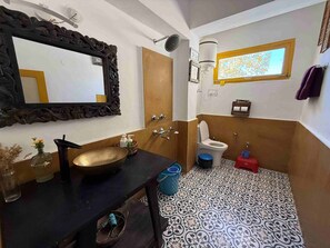 Uma casa de banho com toucador preto, um espelho grande, sanita e azulejos estampados.