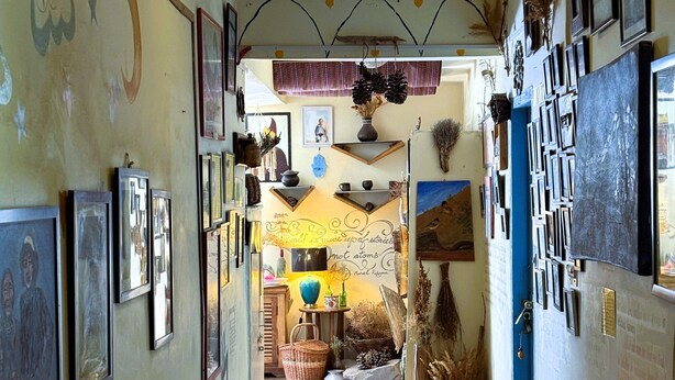Un pasillo con obras de arte enmarcadas en las paredes, un tapete estampado en el suelo y piñas colgadas del techo.