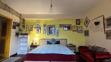 Un dormitorio con cama, un sofá rojo, una mesita de noche y una pared decorada con fotografías.