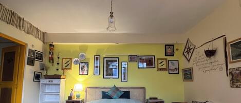 A bedroom with a bed, a red sofa, a nightstand, and a wall decorated with pictures.