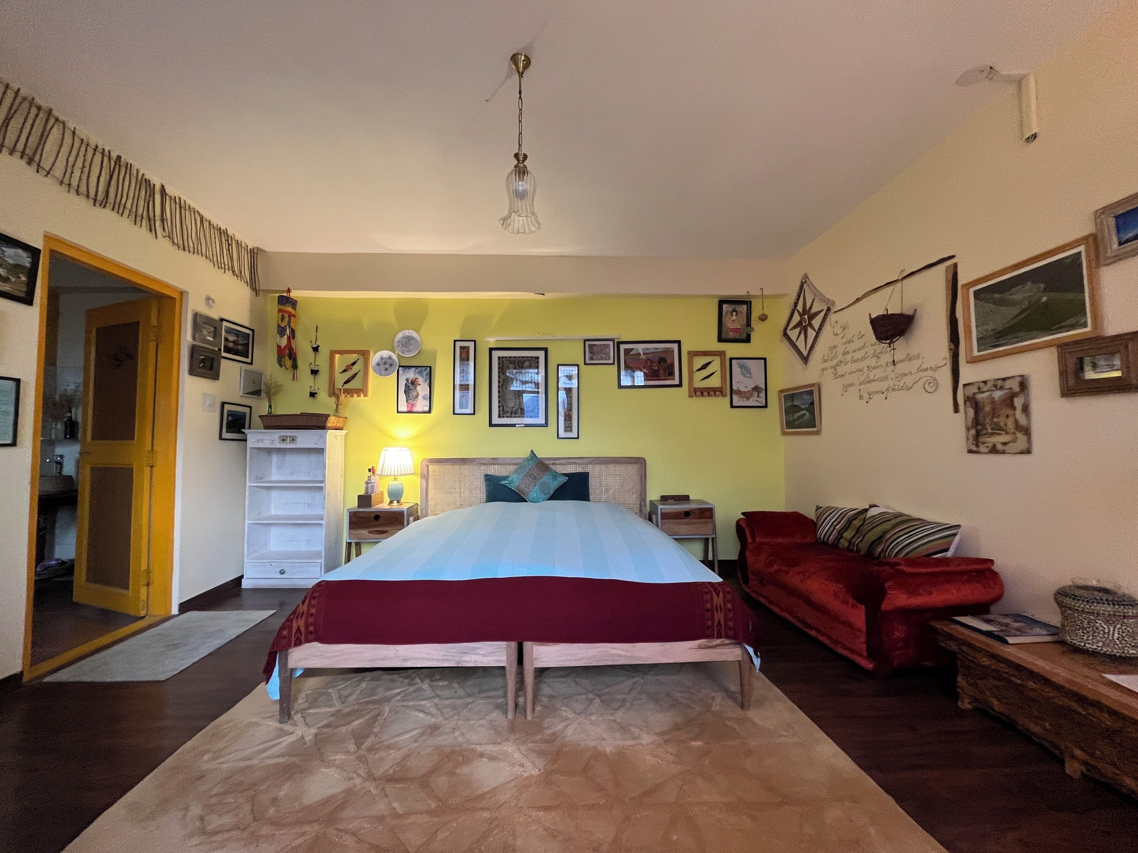 Un dormitorio con una cama, un sofá rojo y una mesita de noche de madera.
