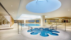 An indoor swimming pool with a skylight, a sunlit area with a canopy, and a spa section with a bed. - Libre Resorts Huangshan (Huangshan)