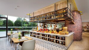 A modern restaurant with a brick oven, wooden shelves with jars, and a view of greenery outside. - Libre Resorts Huangshan (Huangshan)