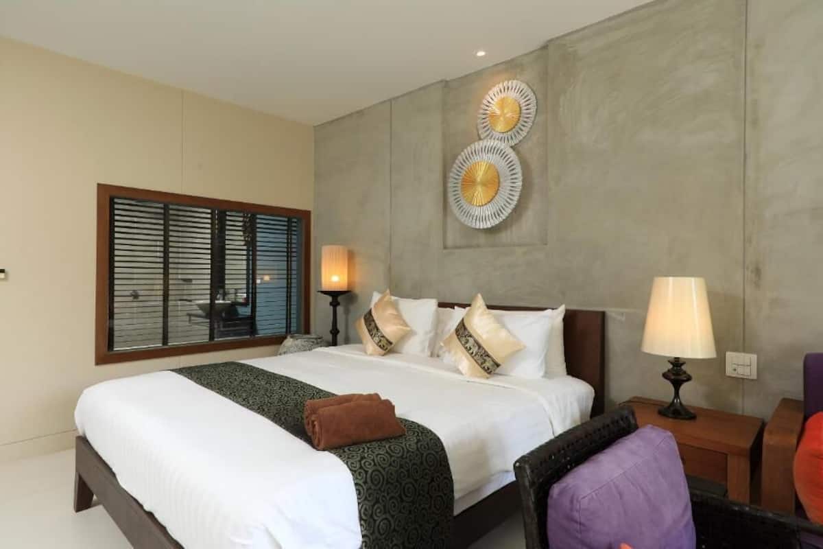 A hotel room with a large bed, two bedside lamps, a wall-mounted decorative piece, and a window with blinds.