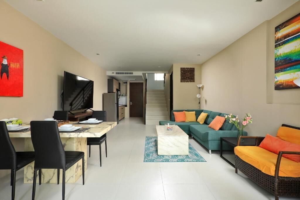 En moderne stue med spiseplads, en sofa, et sofabord og et fjernsyn.