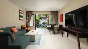 A modern living room with a sofa, coffee table, TV, and dining area. - Tea Tree Boutique Resort (Rawai)