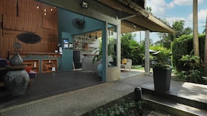 A reception area with a wooden counter, a reception desk, and a view of the garden. - Tea Tree Boutique Resort (Rawai)