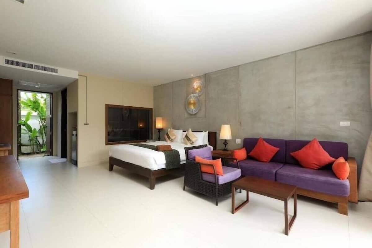 A hotel room with a bed, a sofa, a small table, and a wall-mounted light fixture.