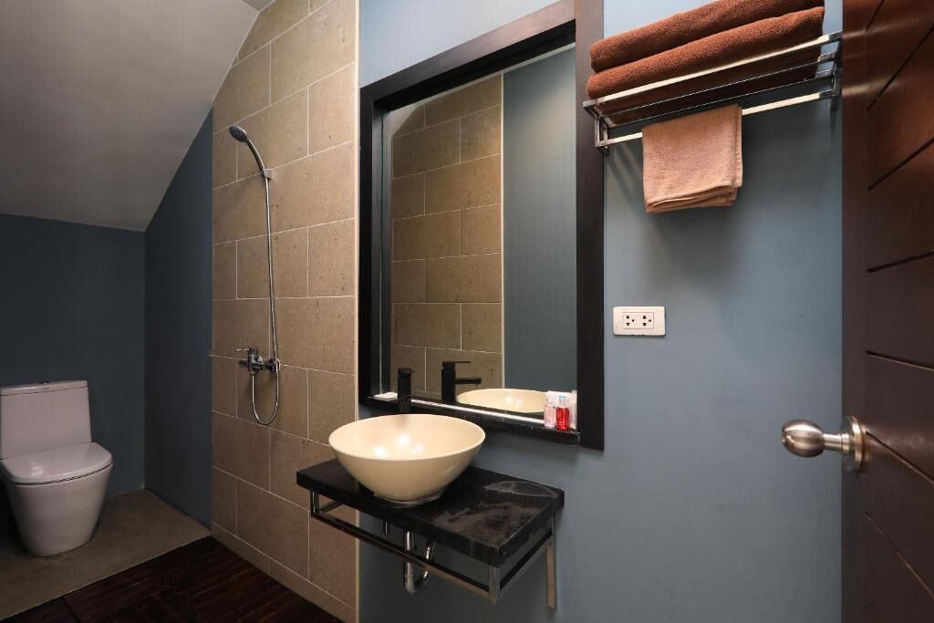 A bathroom with a white sink, a mirror, a towel rack, and a shower.