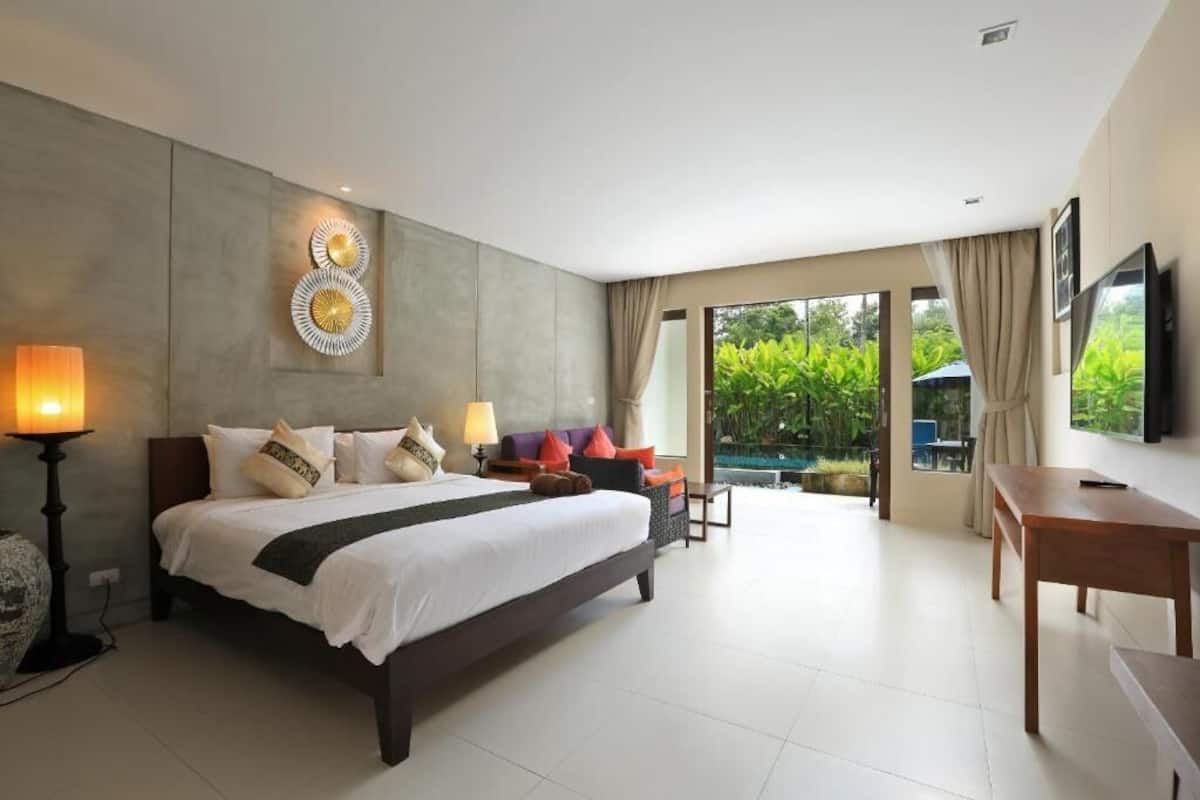A modern hotel room with a large bed, a desk, and a view of a swimming pool.