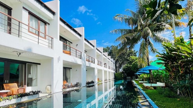 A modern hotel with a swimming pool, outdoor seating, and lush tropical vegetation. - Tea Tree Boutique Resort (Rawai)