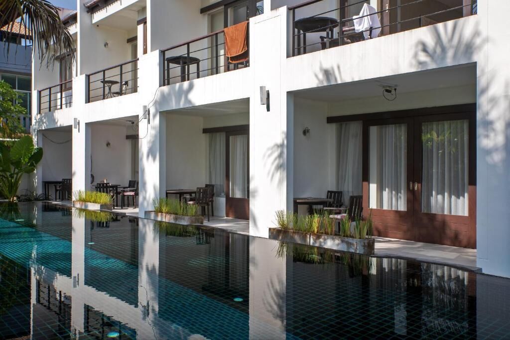 Un hotel moderno con piscina, balcones y zonas de estar al aire libre.