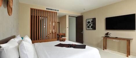 A hotel room with a bed, a wooden partition, a television, and a small table.