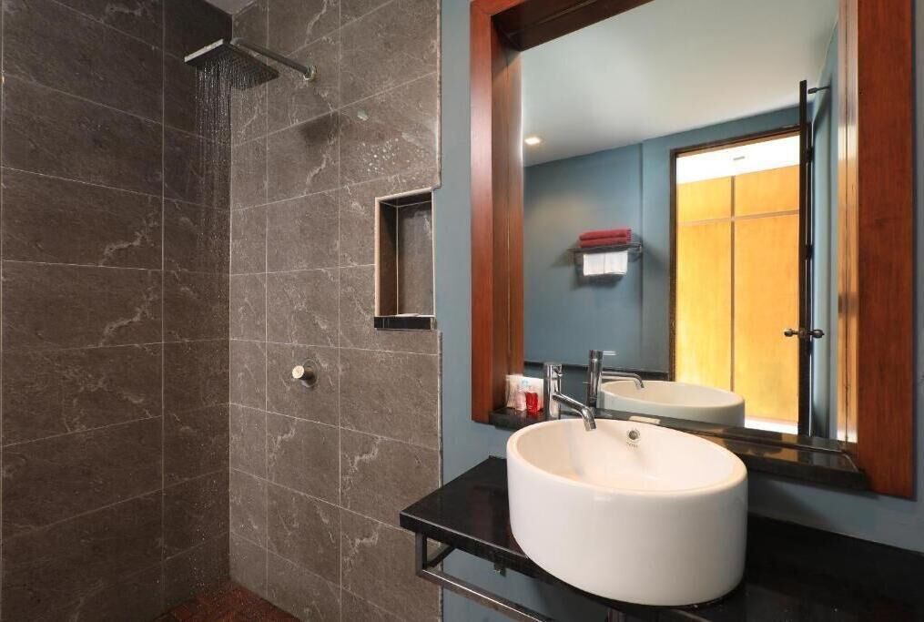 Un baño moderno con un espejo grande, dos lavamanos y una ducha.
