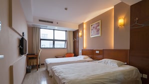 Habitación de hotel con dos camas, un escritorio, una silla, un televisor y una ventana con cortinas.