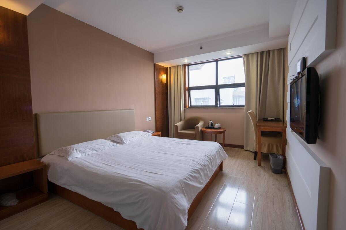 Habitación de hotel con una cama grande, un escritorio, una silla y un televisor.