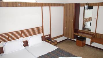 A hotel room with a bed, a bedside table, a mirror, and a small wooden cabinet.