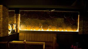 A dimly lit interior with a wall of circular wooden logs and a ceiling fan. - Hotel Prem Nivas (Madurai)