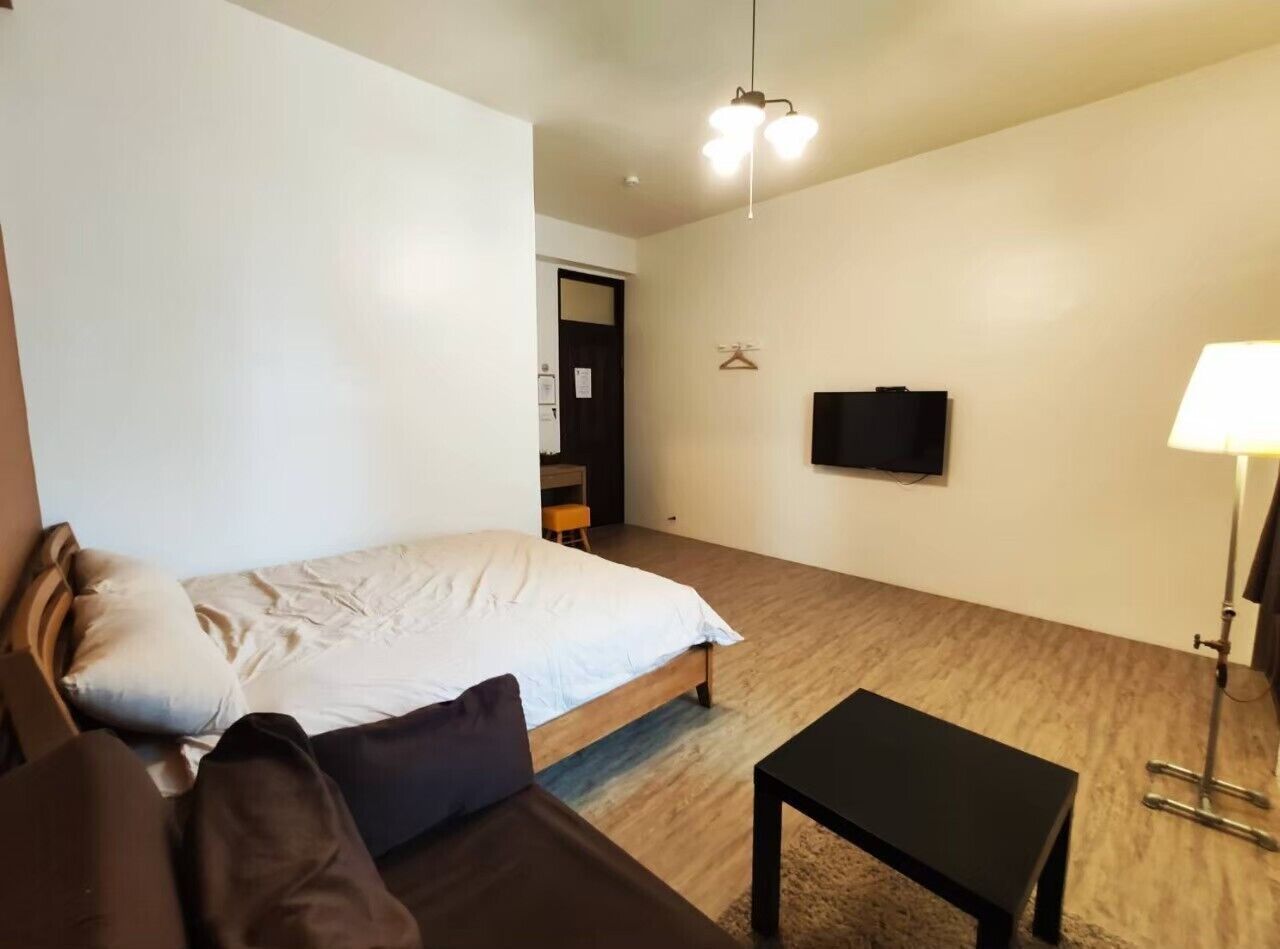 Ett sovrum med en säng, ett skrivbord, en stol, en tv och en lampa.