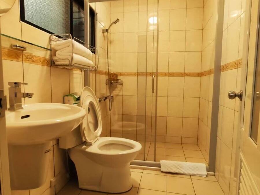 A small bathroom with a toilet, sink, and shower stall.