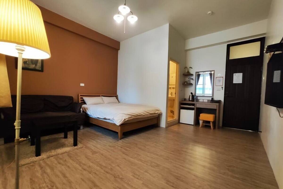 A bedroom with a bed, a desk, and a chair.