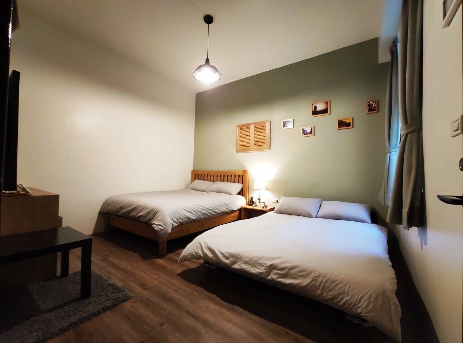 A room with two single beds, a small table, a lamp, and a wooden headboard.