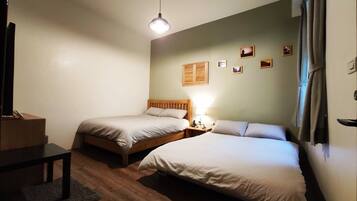 A room with two single beds, a small table, a lamp, and a wooden headboard.