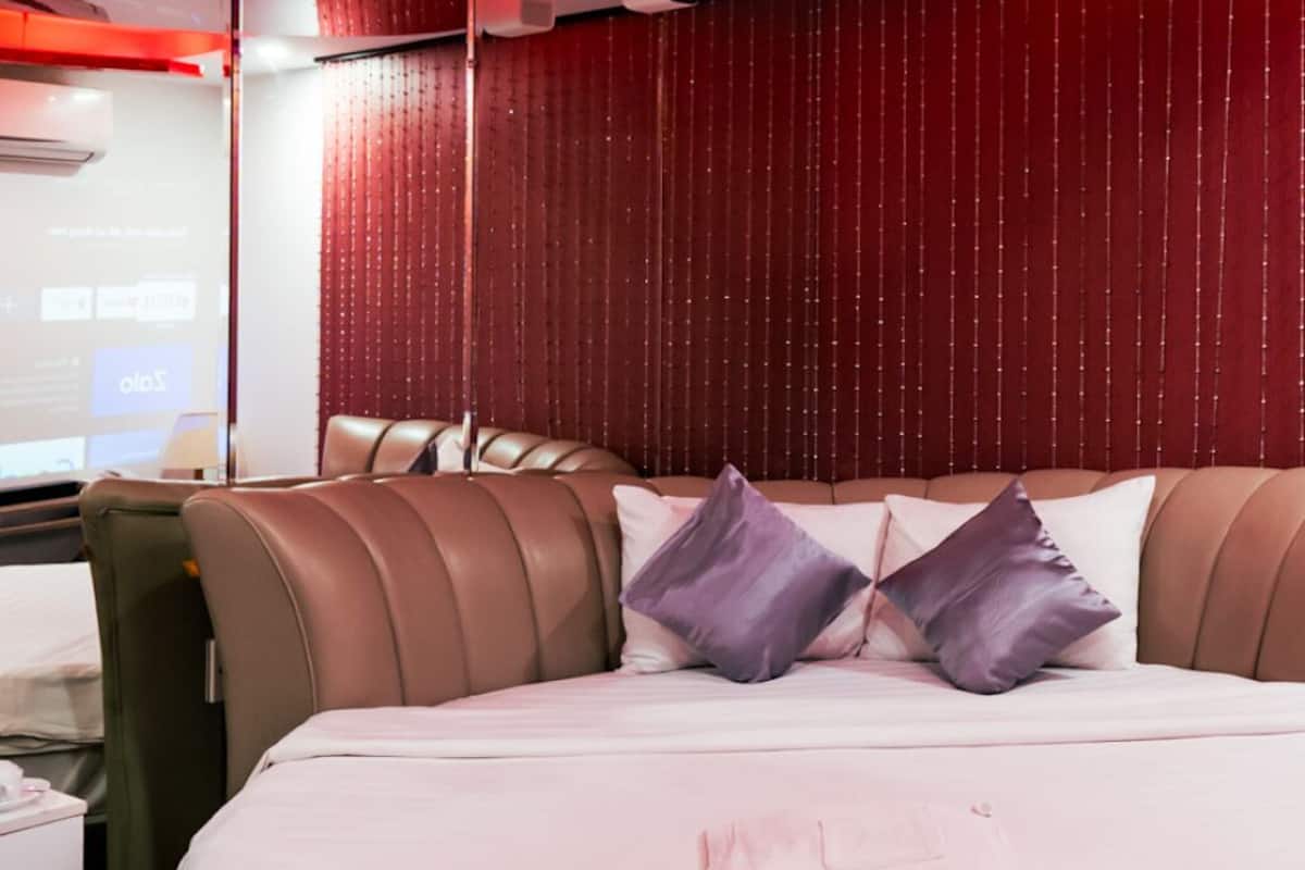 Een hotelkamer met een groot bed, een lederen fauteuil en een rode wandgordijn.