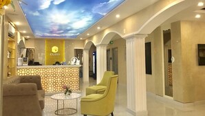 A hotel lobby with a reception desk, seating area, and a ceiling with a cloud design. - Cupid Hotel (Ho Chi Minh City)
