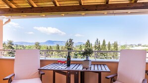 A balcony with two chairs and a table, a bottle of wine, and a potted plant.