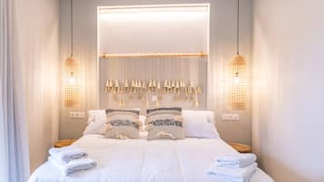 A neatly made bed with white linens and two bedside tables, each with a lamp.