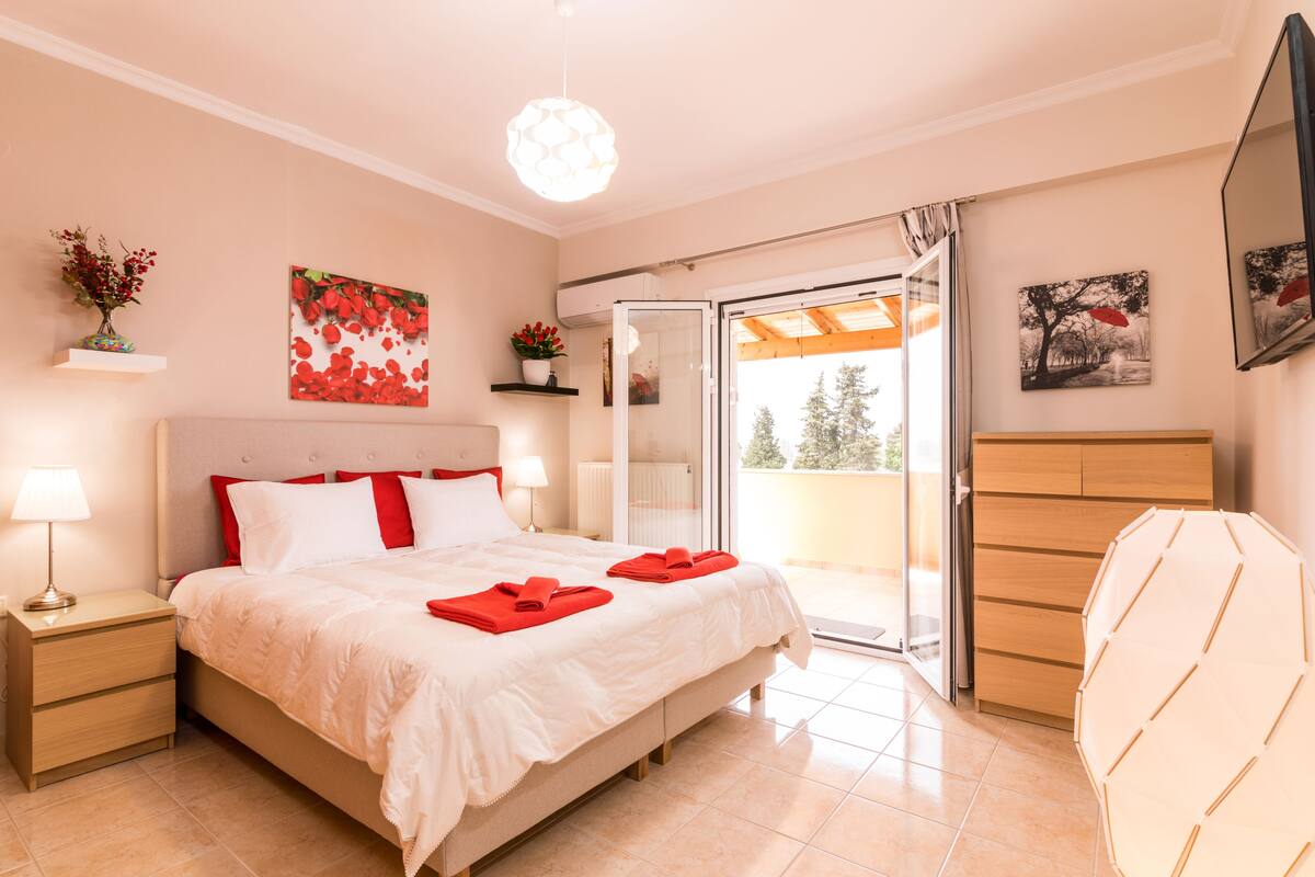 A bedroom with a bed, bedside tables, a nightstand, a window, and a sliding glass door leading to a balcony.