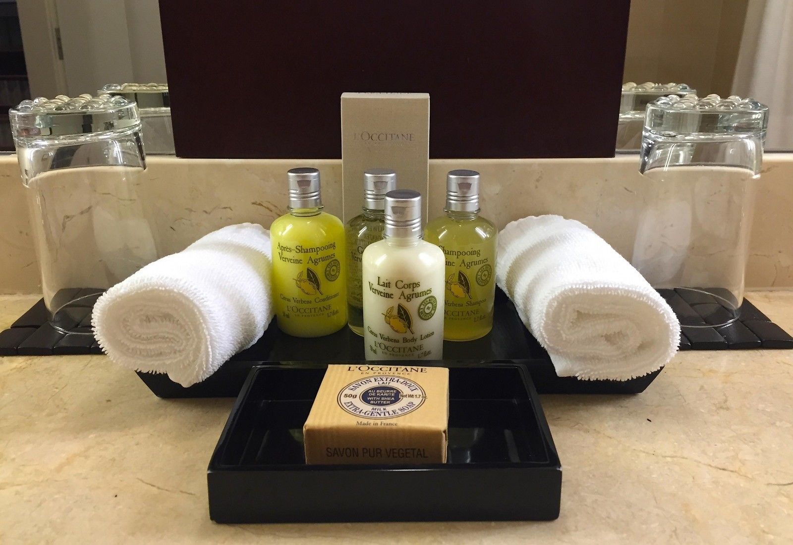 Un ripiano del bagno con articoli da toilette, tra cui due flaconi di shampoo, una bottiglia di lozione corpo e una saponetta.